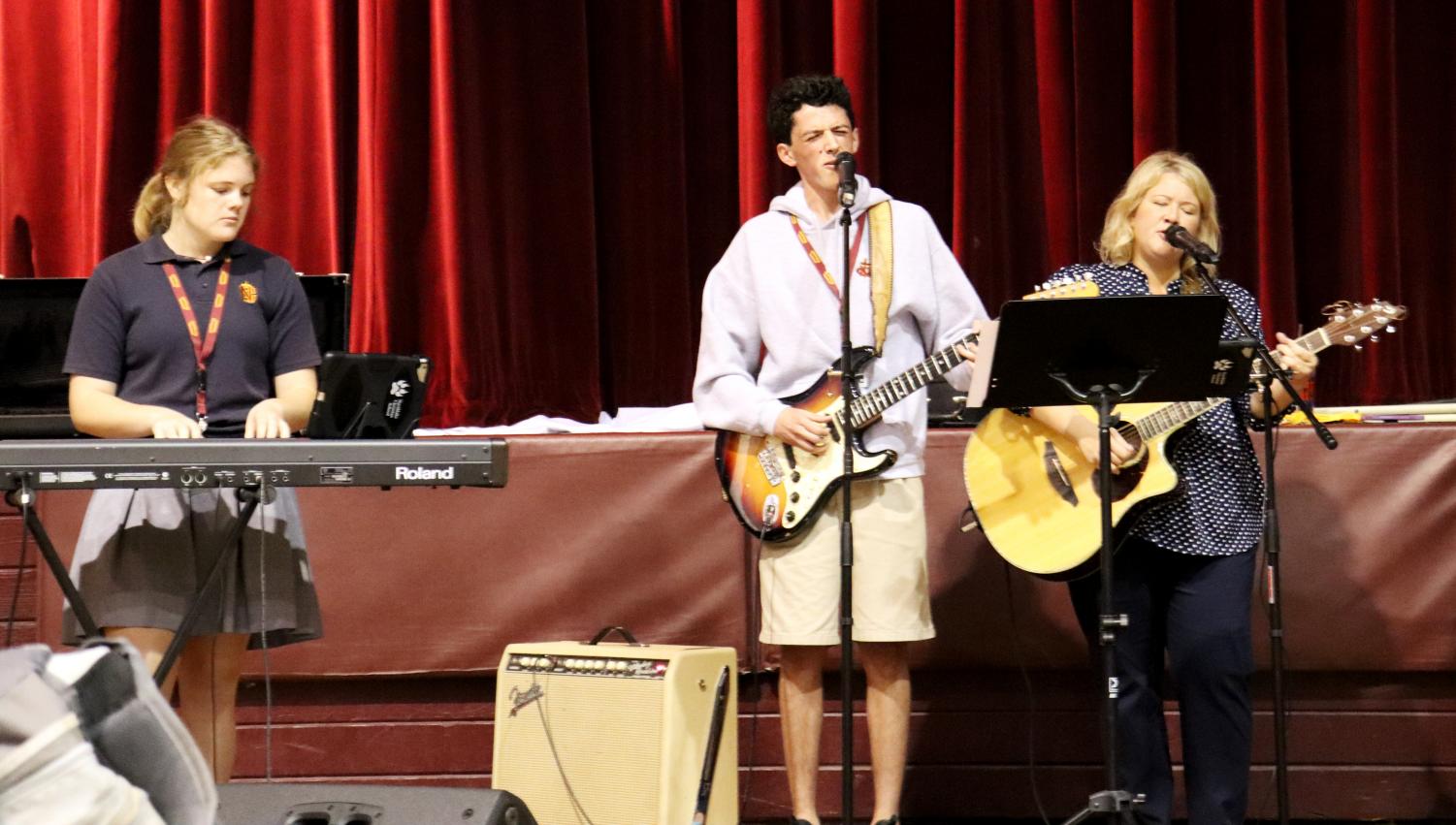 Praise Team member lead worship during Upper School chapel alongside teacher Kate Boudreaux (right).
