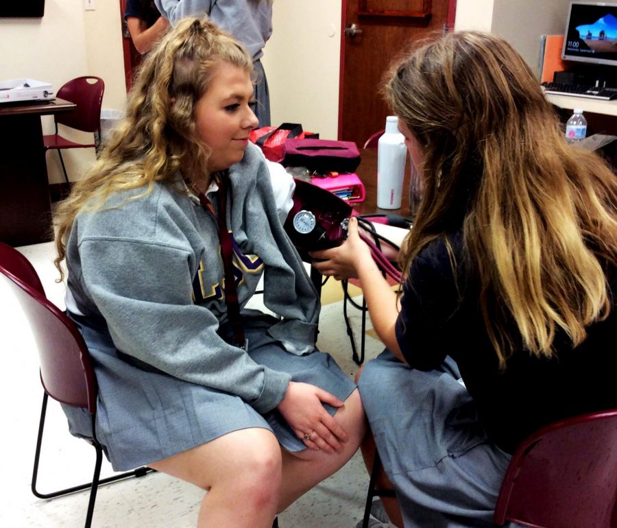 Student Katelyn Simpson practices on Emily Craig during a Certified Nursing Assistant class.