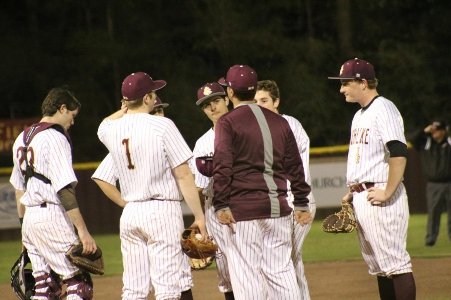 The Wolverine Baseball team gather around the mound mid-game to make adjustments with Coach Cam.