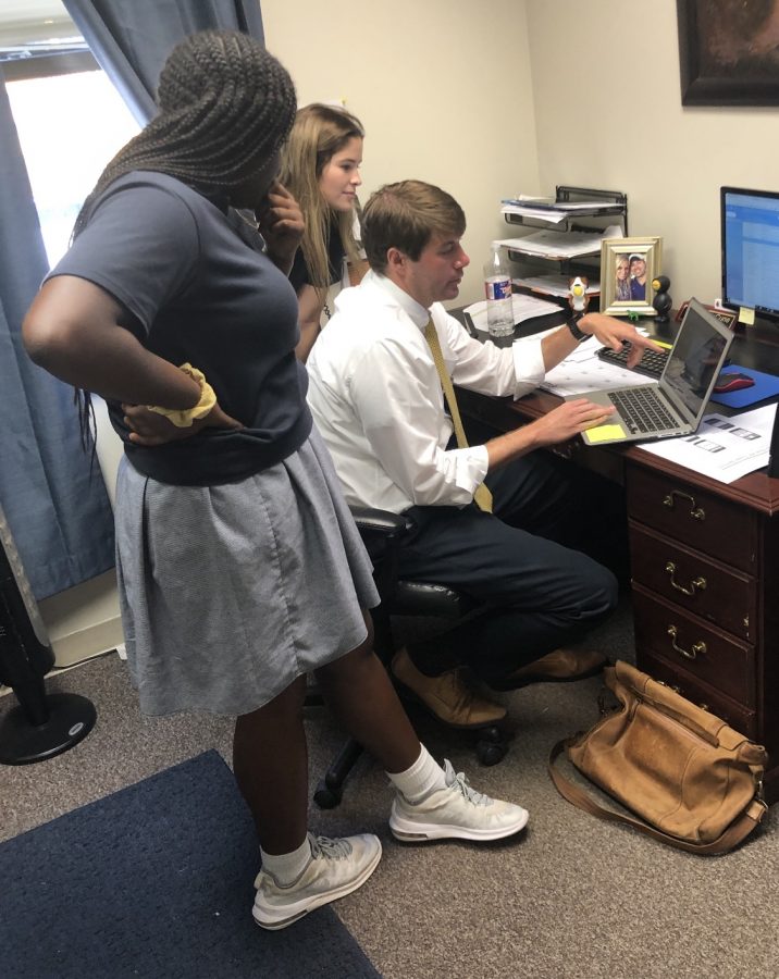 Upper School Academic Dean Matt McCune helps two students in his office.